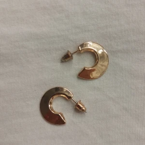 Guldiga Örhängen - Örhängena är helt oanvända. Köpta på Ur&Pen. Borde inte färga av dig vid kontakt med vatten eller nån vätska.