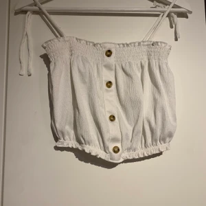 Linne - Linne med brun fläckiga knappar, den är kort i modellen så blir nästan som en magtröja. Banden går att ändra. 