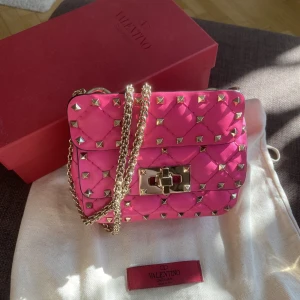 Valentino väska - Säljer min as söta valentino rockstudväska i toppskick då den ej kommer till användning 😓🥲 Bustbag och låda tillkommer, tyvärr är kvittot borttappat. (Men köpt på NK) Helt slutsåld, nypris på farfetch är 16970kr💞 Fler bilder skickad vid förfrågan!