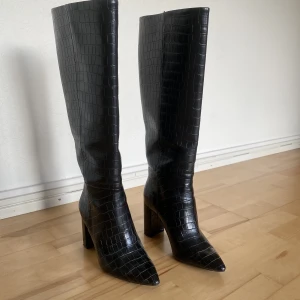 Stövlar med klack - Svarta stövlar i krockodilimitation. Rymligt skaft, spetsig tå och bredare klack. Klackhöjd: 8,5cm. Endast använda utomhus en gång, därav i mycket gott skick. Upplever dem normala i storleken. Inköpspris 800kr. Från H&M💖