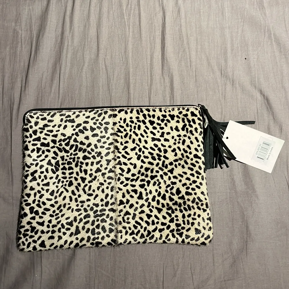 Här har vi en leopardmönstrad handväska ifrån Affari of sweden med svarta detaljer väskan är gjord i fake päls. På insidan av väskan hittar vi korthållare men även stort utrymme för andra föremål samt en ficka med dragkedja, ALDRIG ANVÄND. Väskor.