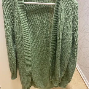 Grön sickad kofta - En grön stickad kofta i storlek S. Har haft den i fyra eller fem månader och är jättebekväm. 