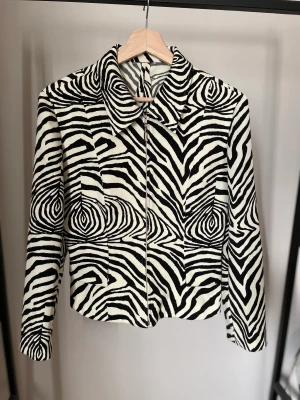 Skjorta second hand - Figursydd skjorta köpt second hand. Skjortan är insydd, finns inget märke/storlek kvar men den passar en xs-s. I färgen är den äggskalsvit och svart, inte kritvit. Fint skick men ett äldre plagg.