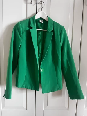 Kavaj - Snygg grön kavaj som passar både till vardag och fest. Köpt för x antal år sen men säljer då jag ej får tillfälle att använda den. Skriv om ni har några frågor!