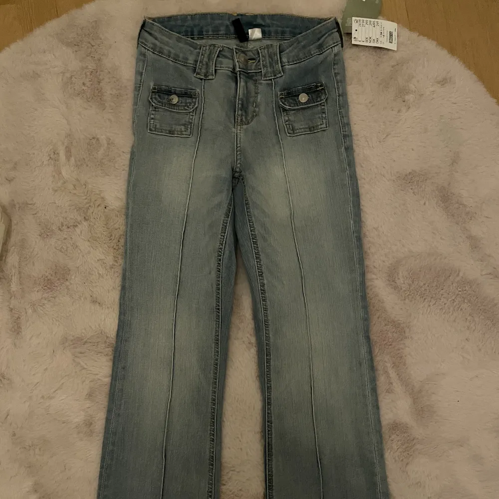 Nyköpta bootcut jeans från H&M och de är inte använda någon gång därav sitter prislappen kvar. Jättesnygg blå tvätt och påminner om 90s. Kvitto finns. Det är storlek 34 men passar även 32 och 36 då de är såpass stretchiga.. Jeans & Byxor.
