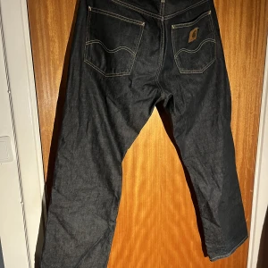 Carhartt texas pant 34/32 - Säljer dessa jeans då de inte kommer till användning. Jeansen är lite bredare i modellen. Storleken 34/32. Inga skador förutom lite slitage i tvätten på färgen längst ner vid fötterna på det vänstra benet. Nypris på dessa är 1400 men säljer dom för 500.