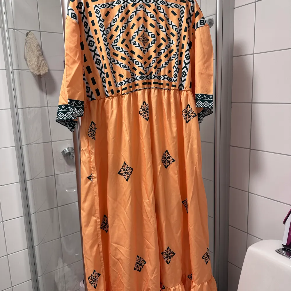 Lång/Modo klänning, färg orange, mönstret.   Använt typ 1-2 gånger så jättebra skick.  Storlek 2-3 XL. . Klänningar.