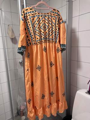 Lång/Modo klänning, färg orange, mönstret.   Använt typ 1-2 gånger så jättebra skick.  Storlek 2-3 XL. 