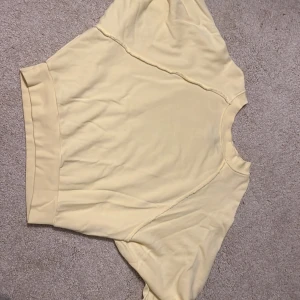 Sweatshirt  - Ljusgul sweatshirt. Sval och skön sweatshirt, som är lite kortare i modellen och med volanger på ärmarna. Bilden ger inte rättvis färg på tröjan så dma vid intresse! 