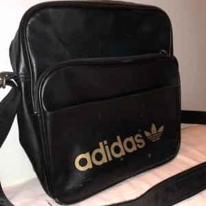 Adidas väska - Inte jätteanvänd. Köpt second hand därav har den några fläckar på framsidan som syns på bilden. Om ni har några frågor är de bara att skriva💕klot för 270kr