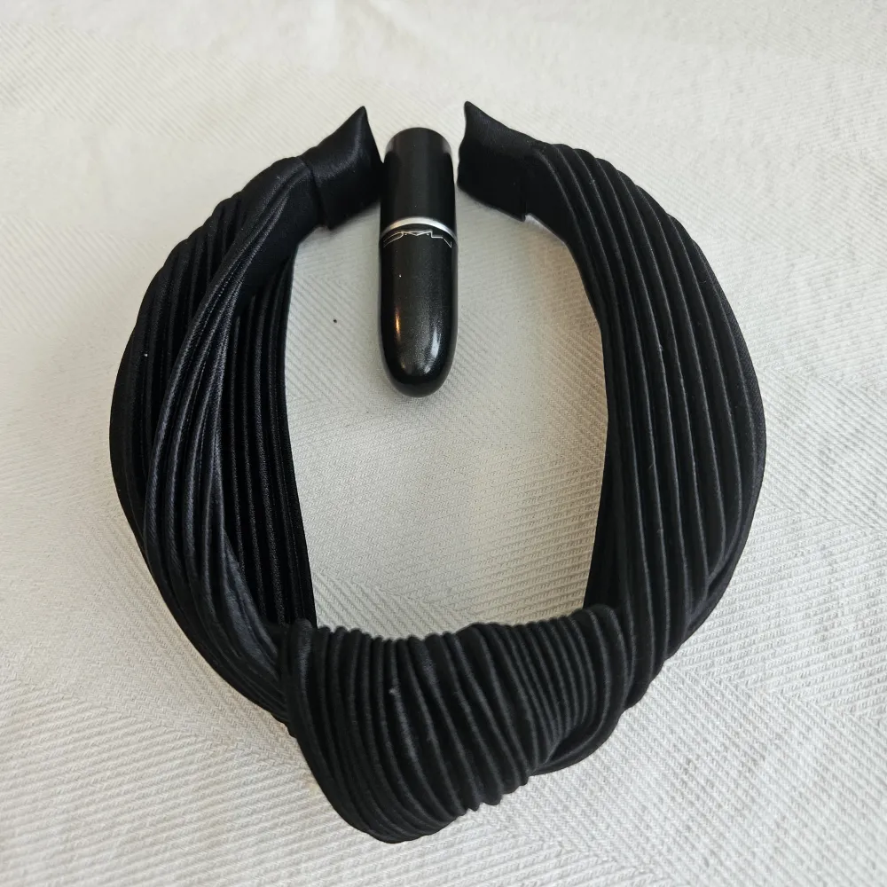 Säljer ett svart diadem med en knut i mitten och ribbad textur. Diademet är ca 2cm på bredden, så ganska tjockt.   Passar lika bra med pärlörhängen som till en mer bohemisk look.. Accessoarer.