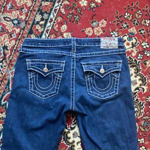 Säljer sjukt snygga blåa true religion jeans i storlek 33. Aldrig använda, köpta second hand :) Modellen är skinny och lågmidjade, perfekta för boots! Bakfickorna har knappar. Midjemått 45 cm tvärsöver, innerbensmått 78 cm🫶🏼Kan såklart skicka fler bilder!