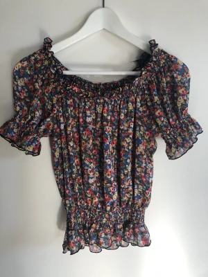 Blus  - Blommig blus - kan användas som offshoulder och croppad 