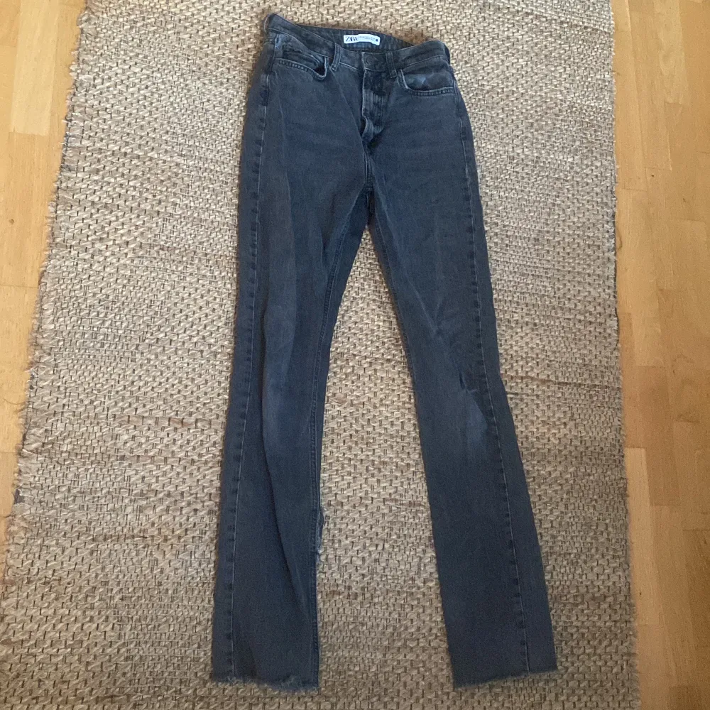 Ett par svarta jeans med slits längst ner på under sidan. Jeans & Byxor.