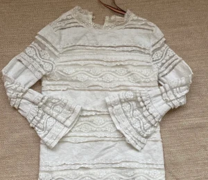 Vit blus - En fin vit tröja med utsvängda armar längst ut och väldigt fina detaljer💗 tyvärr lite prickar av färg på framsidan men inget som syns jättetydligt. Passar även 134….Gratis frakt❤️skriv om ni undrar något👍🏼kan självklart diskutera pris!