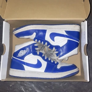 Jordans 1 mid  - Säljer dessa sneakers från Nike Jordans womans air 1 mid, i färgen white/ hyper royal. Skorna är använda och det finns tecken på viss slitning men generellt är dem i bra skick! Kvitto har tyvärr försvunnit men skorna skickas med i orginalkartongen!