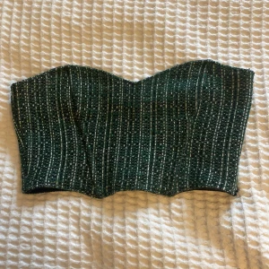 Kroppad topp - Kroppad topp i grönt/svart/vitt. Har en dragkedja längs sidan. Jättesnygg passform!