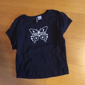 Svart t-shrit - Svart t-shirt med fjäril, endast använd 1 gång super fint sckick.