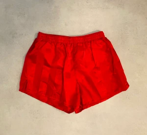 Vintage glansiga shorts - Röda vintage shorts från 1980-talet i glansigt polyester tyg, storlek M men mer som S. Bra skick, bra resår! Verkar knappt använda 