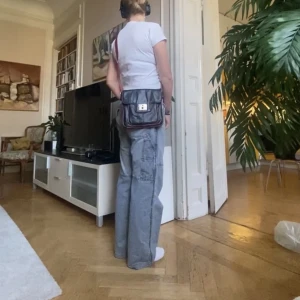 Svartröd axelremsväska - Svart axelremsväska med rött band och fina detaljer. 