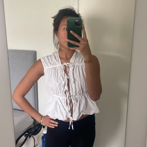 Vit tröja - En vit tröja med tre rosetter där man själv justerar. Det är tjockare material. Den är väldigt bekväm och fin när den är strykt😅