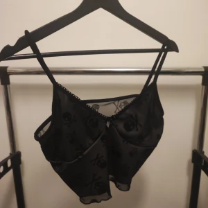 Topp med dödskallar  - VÄNTA PÅ SVAR FRÅN MIG INNAN KÖP! Söt svart topp med dödskallar. Lite mesh liknande material.