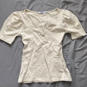 Topp - En topp från NAKD som uppenbarligen inte är struken, men lika fin ändå! Har lite puffiga axlar. Använd fåtal gånger och i fint skick 🧡