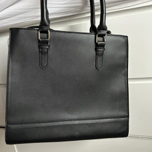 Väska - Stilren svart väska! Ett ytterfack och några innerfack (se bild). Medföljer ett justerbart axelremsband. Sparsamt använd❤️