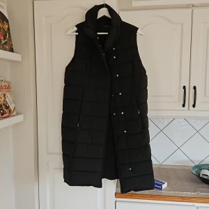 Dunväst - En längre väst med dubbelknäppning....som magnet knappar. Fint skick då den endast använts max 5 gånger. Stor i storleken.