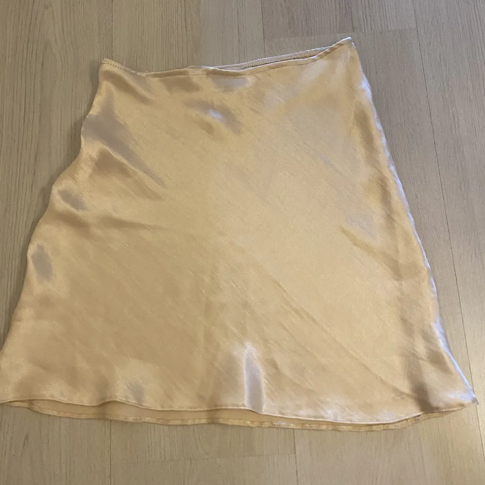 Kort siden kjol med resår i midjan. Vit/Beige/rosa färg . Hameet.