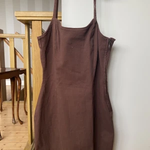 Figurnära Brun Jeansklänning - En brun jeansklänning som följer ens kropp och är figurnära. Storlek 38. Knappt använd