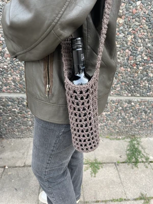 Handgjord virkad väska - Handgjord virkad väska som rymmer en vinflaska eller annan flaska i liknande storlek. Finns i flera färger. 100% recycled cotton. Kan bäras cross-over eller på en axel.