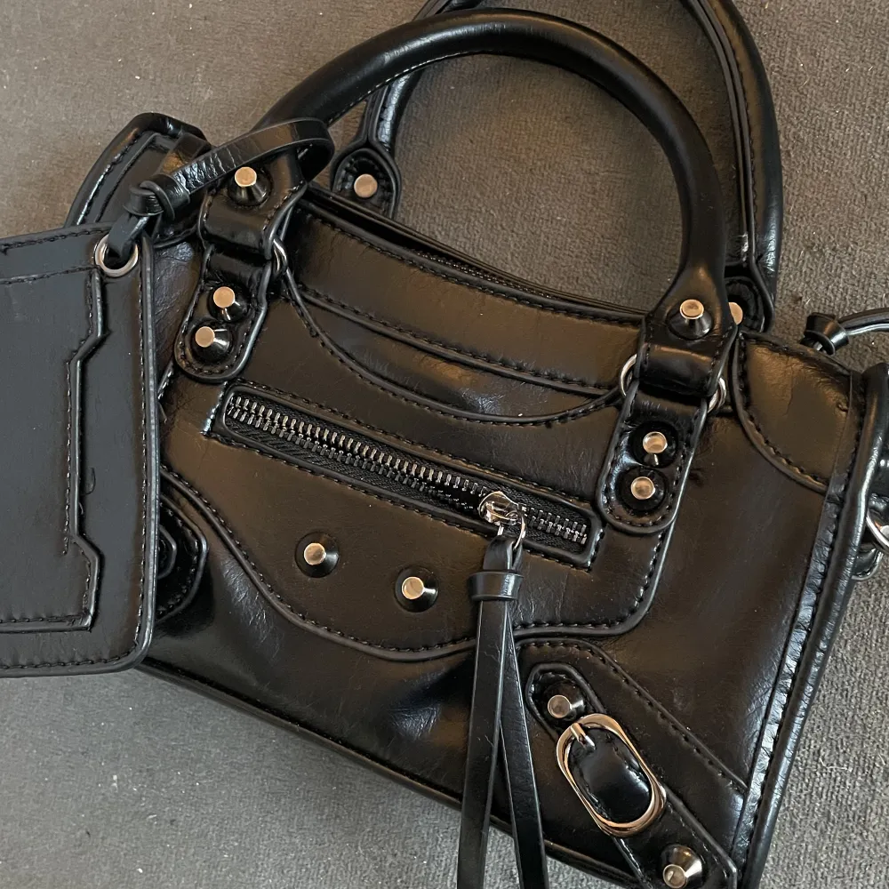 En svart liten Balenciaga liknande väska! Helt oanvänd, så därav mycket fint skick <3 Medföljer långt axelremsband . Väskor.