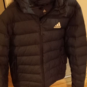Adidas vinterjacka, mörkgrön - Varm vinterjacka, två mindre revor se bild 3. Upplevs lite liten i storleken.