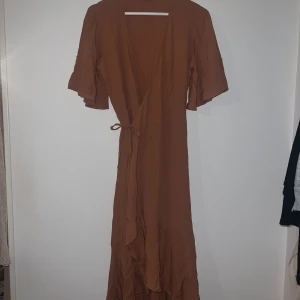Omlott klänning  - Fin klänning från Carin Wester, klänningen är omlott och är i en ljus orange/korall färg (ljusare än på bilden) den är i storlek 36 men eftersom den är omlott så kan man välja lite hur den ska sitta, extremt skönt tunt material till sommaren 