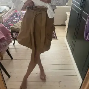 Fin beige/brun kjol med knapp och bälte från HM Helt oanvänd med prislappen kvar. Storlek: 36 100% bomull 