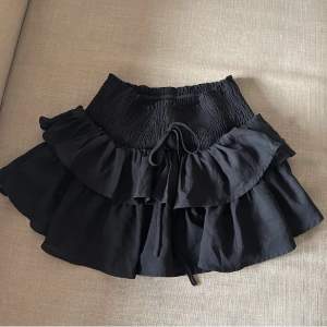 En svart kjol, lite kortare i modellen men det är också byxor under. 
