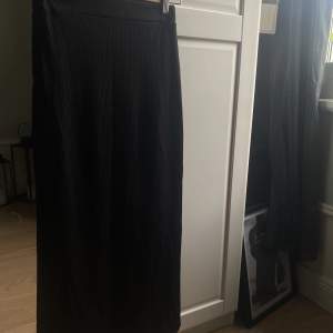 Lång ribbad svart maxi kjol med en slita på en sidan. Har en tajt passform trotts slitsen, jättefin på men är för liten för mig