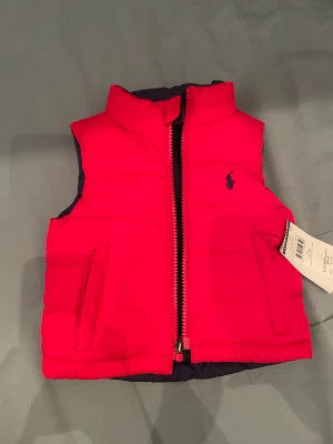 Ralph Lauren väst  - En helt ny Ralph lauren väst för bebisar. Kan böjas in och ut och skyfta från röd till mörkblå väst. Ser och känns super skön och perfekt för hösten! Funkar BÅDE för flickor och pojkar. Köpt på REA för 850 kr då vanligt pris är 1150kr, 