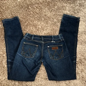 Low waisted jeans med fickor - Säljer ett par low waisted jeans från wrangler i storlek W27 L32. Kontakta mig för mer bilder 💗 Köpta för ca 1000kr. De är i mörkblå! (Obs) De är sydda i midjan, men man kan säkert lossa bort det!
