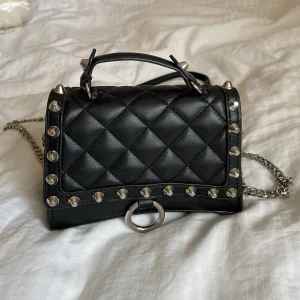 Svart väska med nitar - Säljer nu denna skit coola väskan från Zara. Nypris ca 350kr🤗Super najs till våren och sommaren, passar perfekt till en  t.ex! Använd vid enstaka tillfällen, sparsamt. Längd ca 18cm, höjd ca 12 cm💫