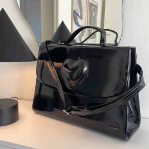 Svart stor väska! - Säljer denna super coola väskan i lack då jag inte längre använder den. Den är stor och rymlig perfekt att ha sin dator i. Det finns lite slitage och repor dock inget jag tycker är överdrivet, fin insida. Är ni intresserade kan jag slicka mer bilder!