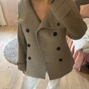 Beige Kappa  - Fin kappa som är perfekt under våren och hösten. Den är i fint skick och säljs pga att den inte kommer till användning.