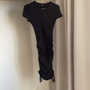 Klänning  - Svart klänning från SHEIN i storlek S med snören på sidorna. Klänningen går att förlänga och förkorta. Använd någon ensaka gång förra sommaren! Nypris 149kr