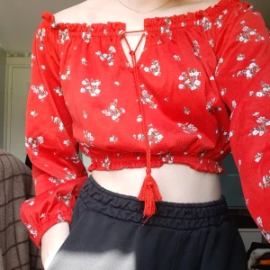 Röd blommig blus - Röd blommig kort blus med knyte och lång ärm. Fin tröja nu inför sommaren. Den är använd ett fåtal gånger och nu har den inte kommit till användning på länge, just därför jag säljer den. Skriv för mer info och bilder❤🌹
