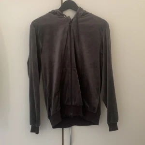 zip tröja - Det är en mörkgrå zip up tröja med snören, 2 fickor och luva.