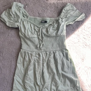 Klänning  - Så söt klänning i en jättefin grön färg med gulliga detaljer, passar perfekt nu till sommaren och kan även användas som kjol. Har knappt använt den så den är i fint skick!Skriv för fler bilder eller frågor🥰