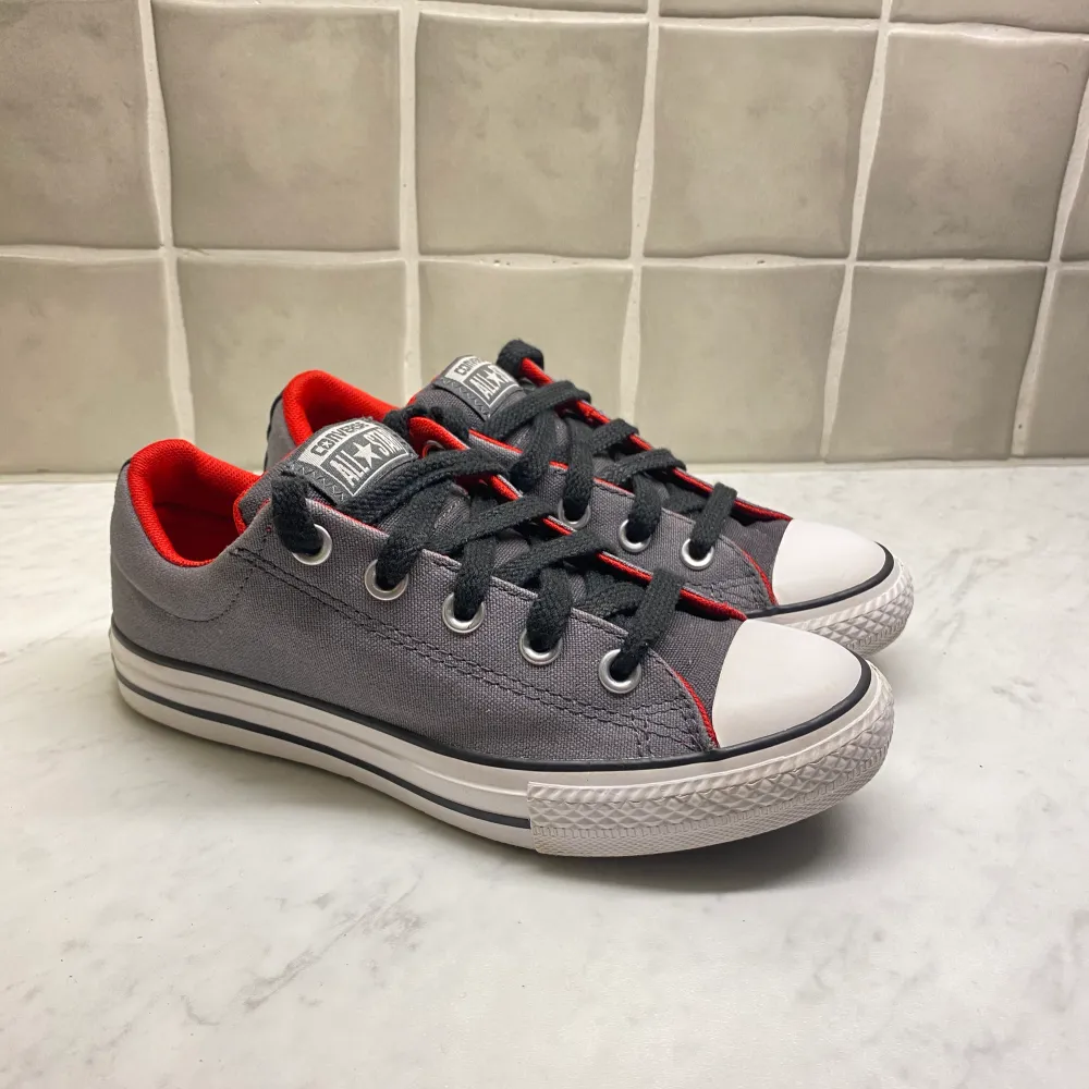 Säljer ett par nästan nya låga converse som är grå med rött på insidan. Endast testade utomhus en gång.  Pris kan diskuteras!!!. Skor.