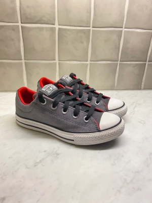 Grå låga converse  - Säljer ett par nästan nya låga converse som är grå med rött på insidan. Endast testade utomhus en gång.  Pris kan diskuteras!!!