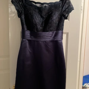 Marinblå cocktail klänning  - Off shoulder knälång cocktailklänning i satäng med spets upptill. Använd en gång. Dragkedja bak